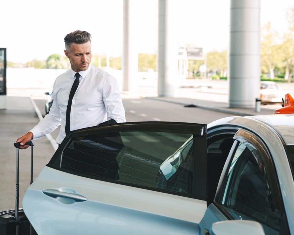 Handsome,Mature,Businessman,Getting,In,Taxi,Outside,The,Airport,With